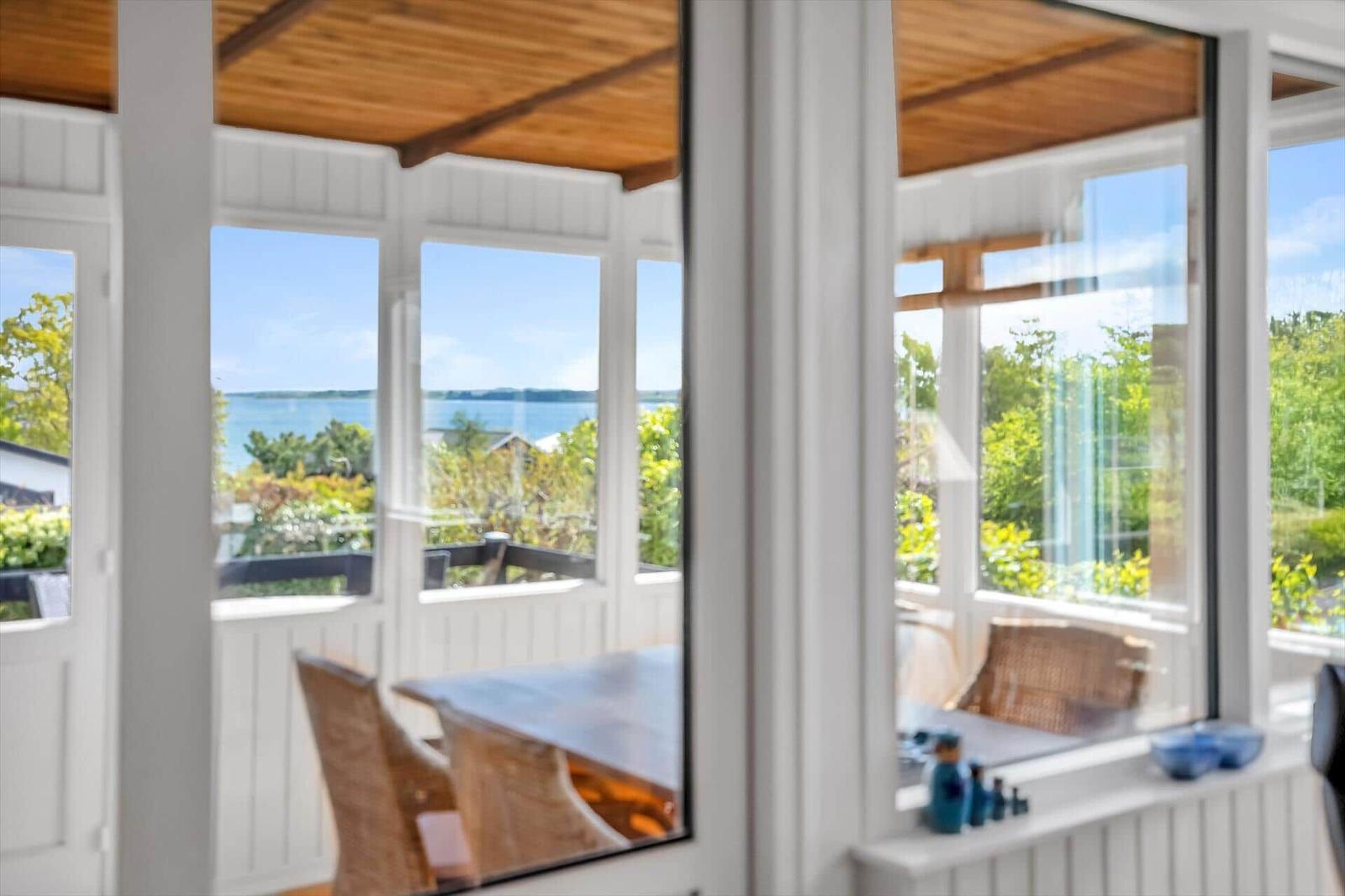 Terrasse mit Tisch und Stühlen, Blick auf Wasser und Grün