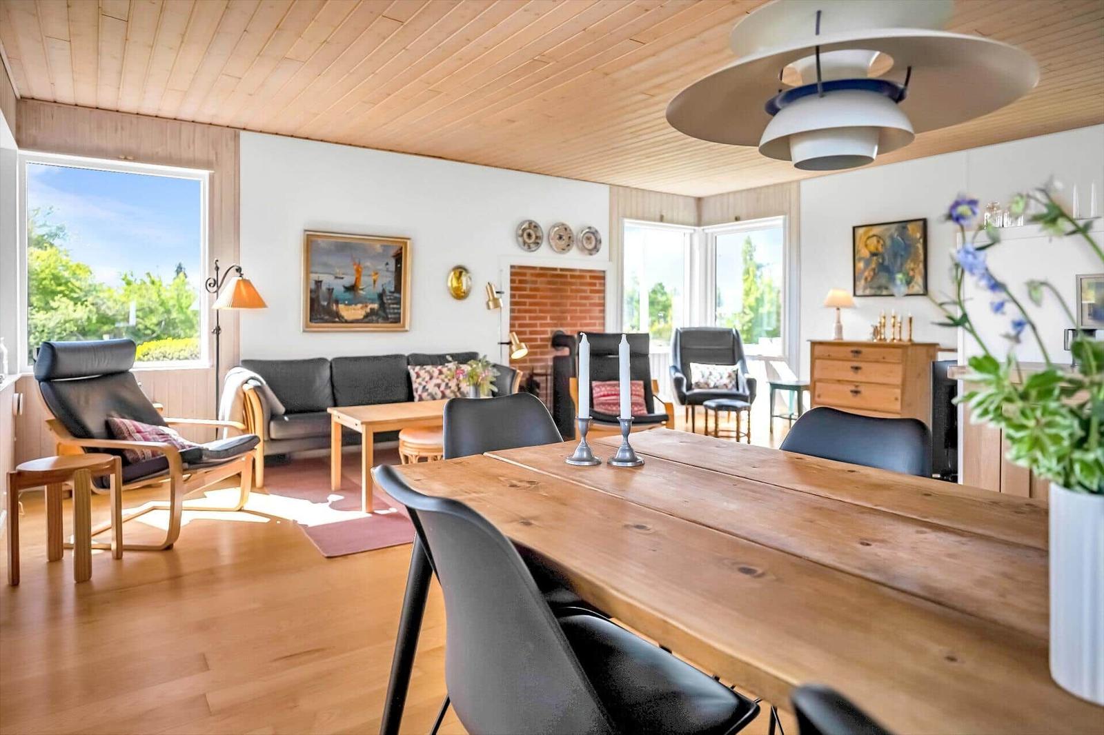 Esszimmer mit Holztisch und Stühlen. Wohnbereich mit Sofa, Kamin und Fenstern.