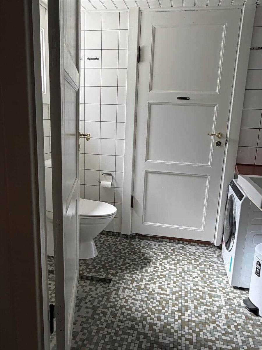 Badezimmer mit Toilette, Waschmaschine und Mosaikfußboden.