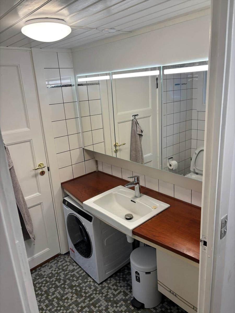 Badezimmer mit Waschmaschine, Spiegel und Toilette