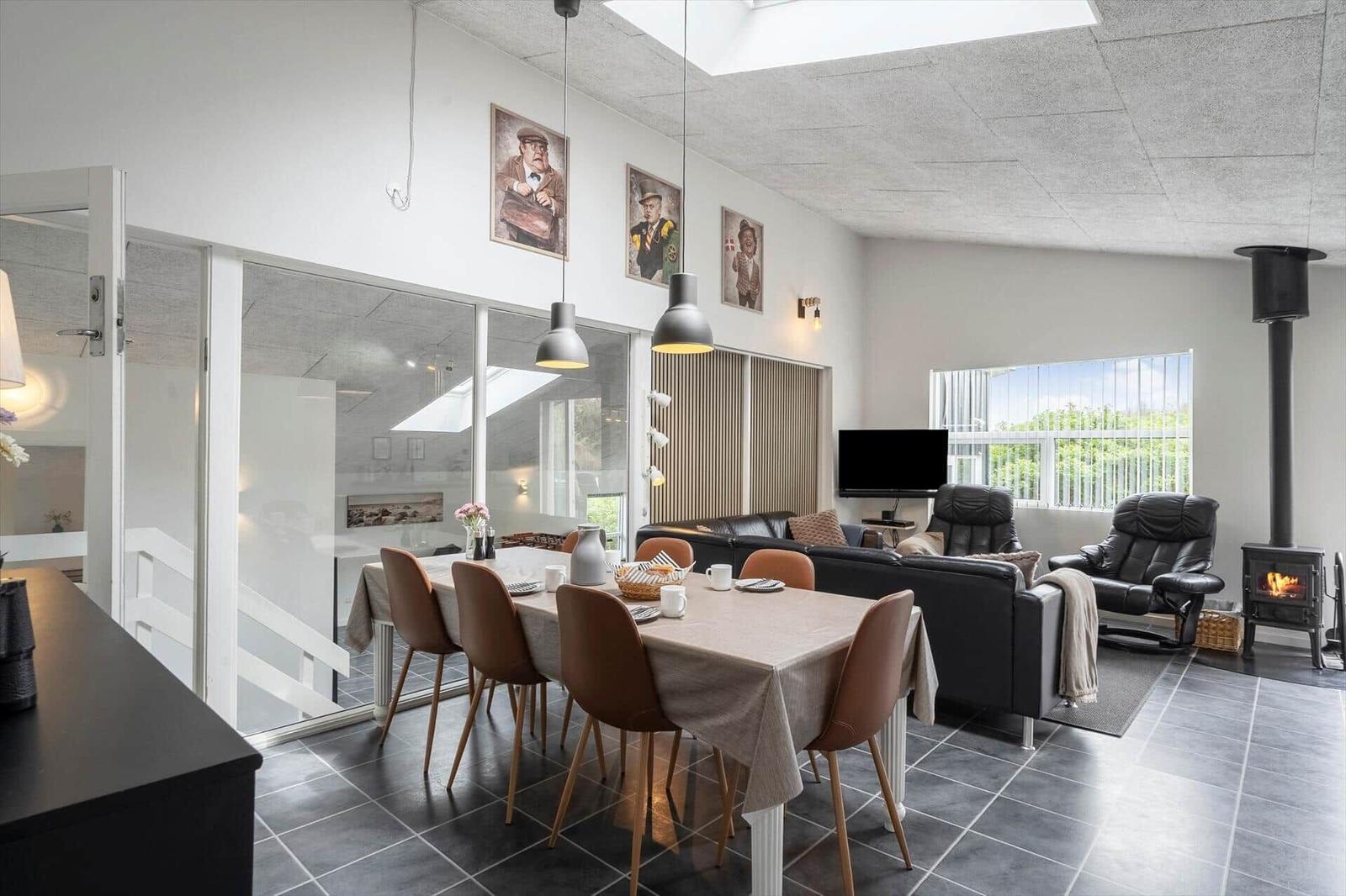 Essbereich mit Tisch und Stühlen, Wohnzimmer mit Sofa und Kaminofen.