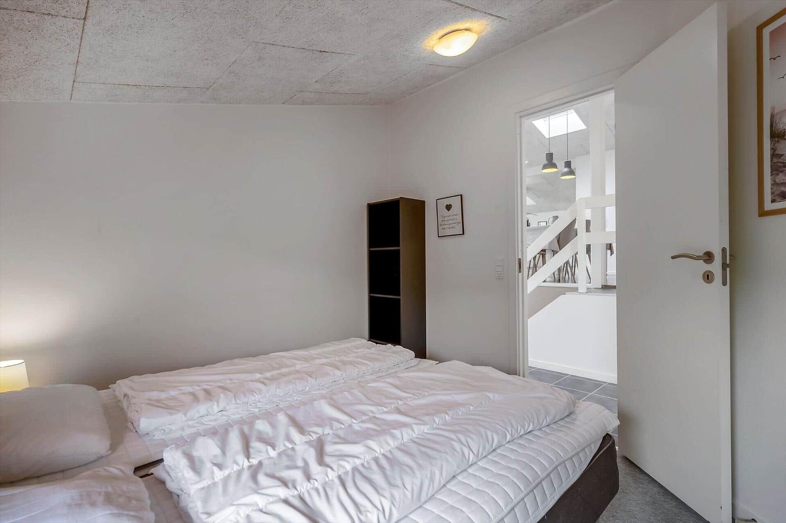 Schlafzimmer mit Bett, Kleiderschrank und Tür zum Flur.