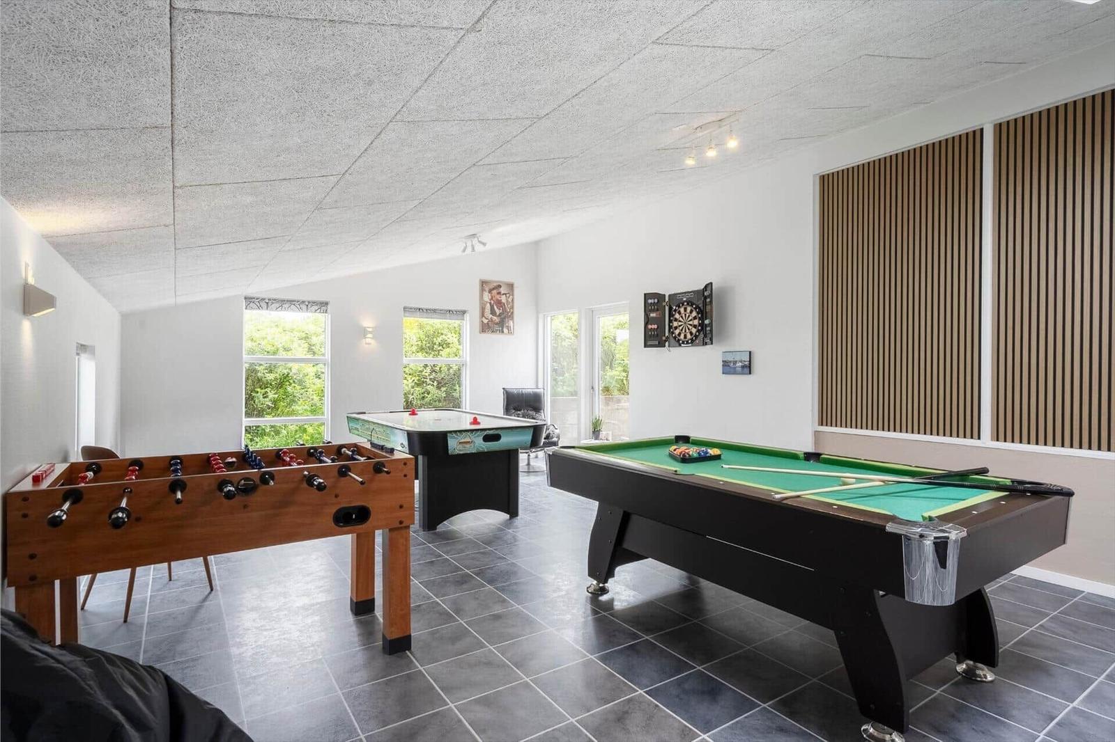 Raum mit Billardtisch, Tischfußball und Dartscheibe. Fenster mit Blick auf Grün.