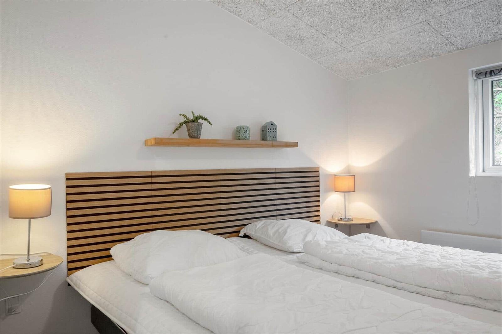Schlafzimmer mit Doppelbett, Holzkopfteil und Nachttischen mit Lampen.