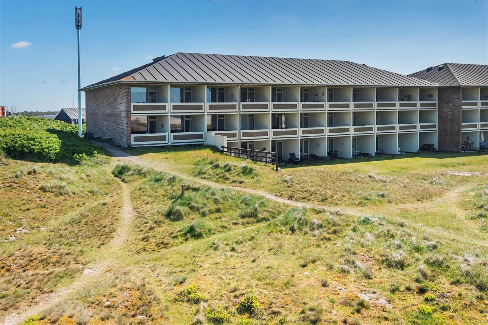 Ein mehrstöckiges Ferienhaus mit Balkonen liegt auf einer grünen Wiese.