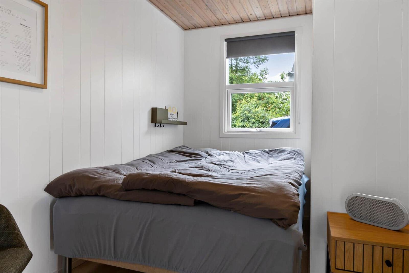 Bedroom with bed, window, and nightstand.