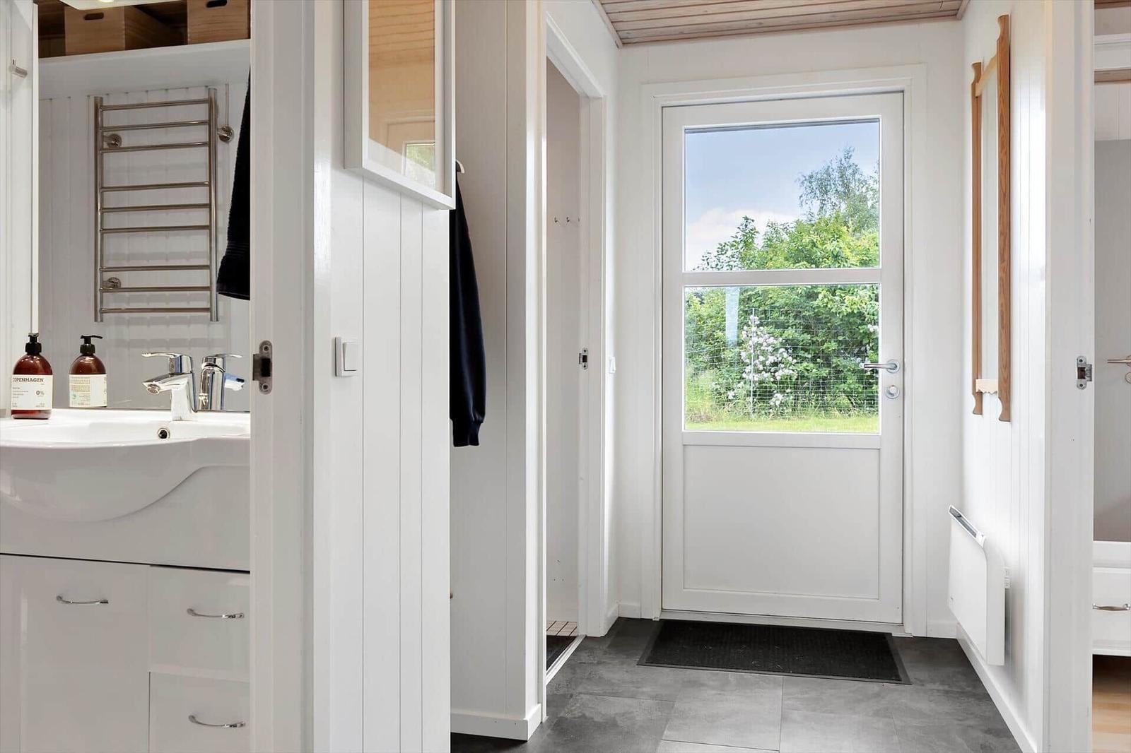 House with entrance door, sink, and view of green area.