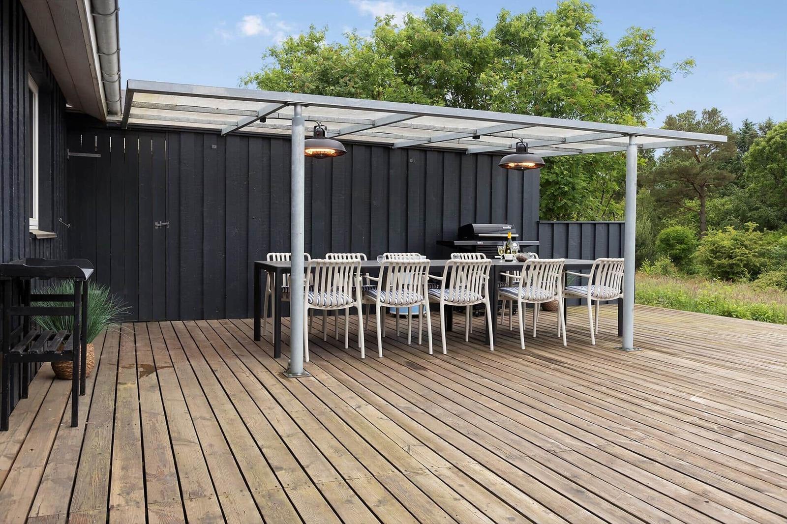 Deck with table, chairs, grill, and pergola under blue sky.