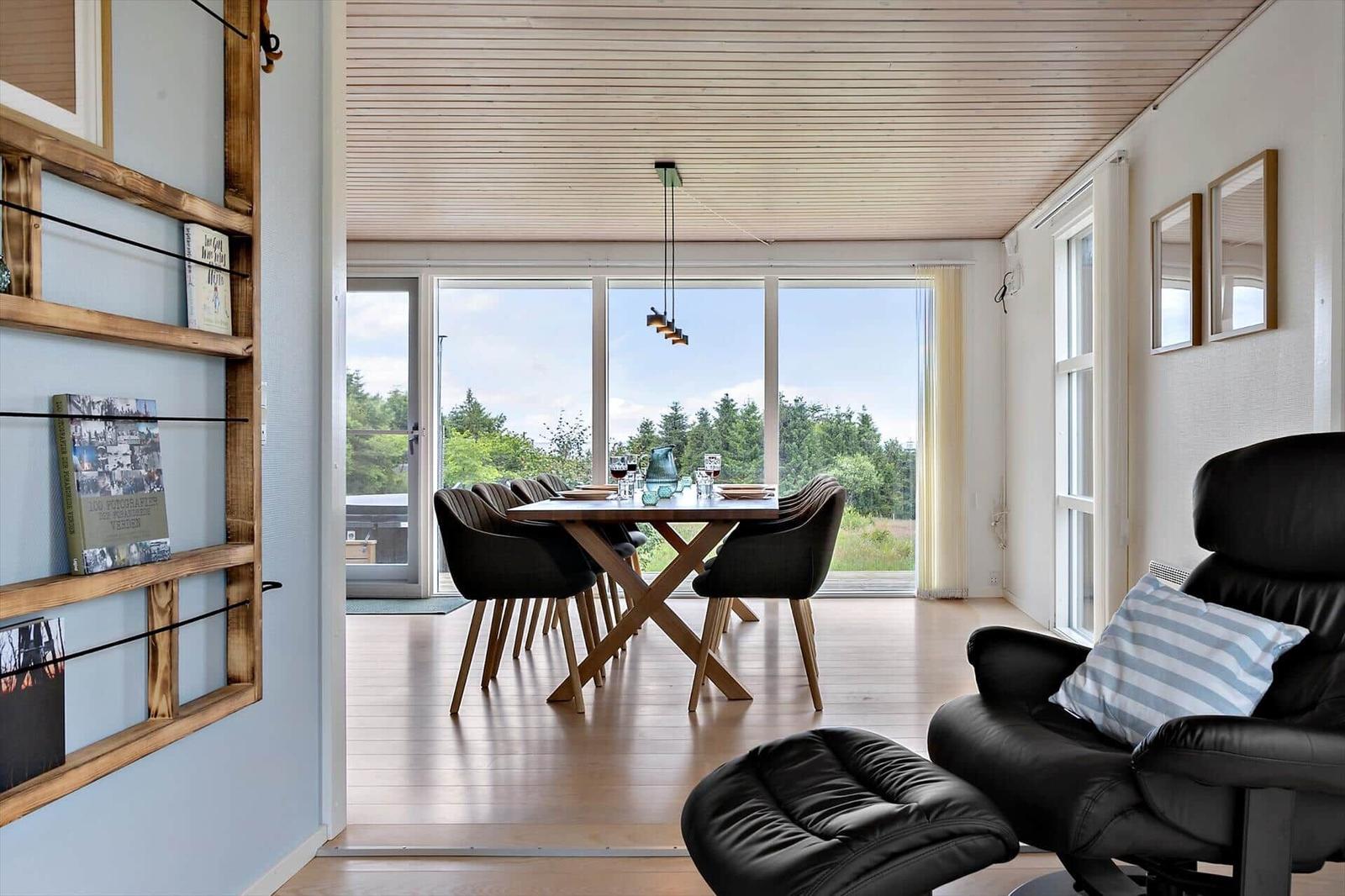 Dining room with table, chairs, and view of forest. Black leather recliners in foreground.