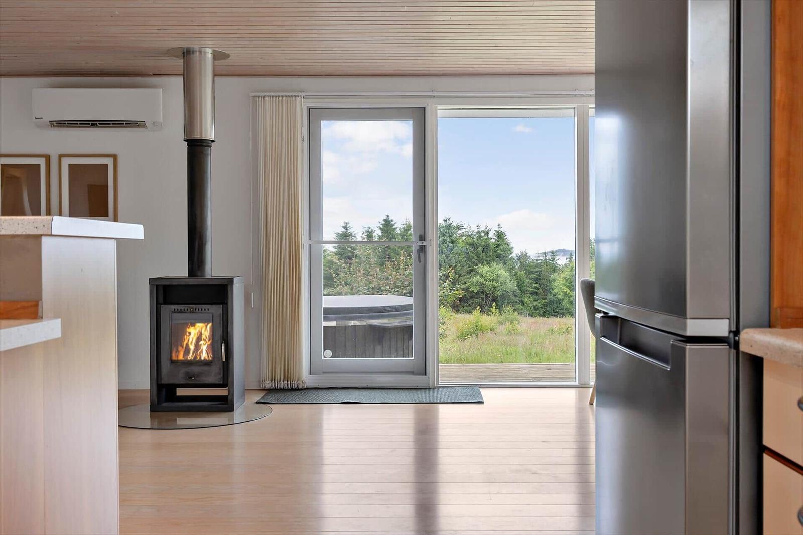 Room with fireplace, refrigerator, and view of garden.