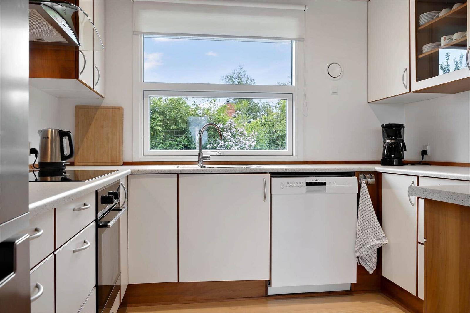 Kitchen with window, sink, dishwasher, and cooking appliances.