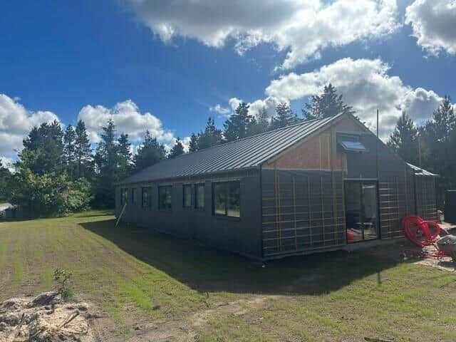 Moderne Holzhütte mit großem Fenster und Terrasse im Wald