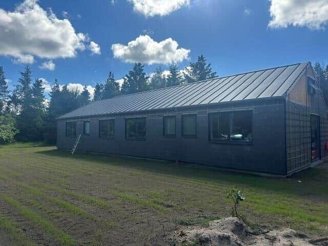Moderne Hütte mit Metalldach und großen Fenstern im Wald