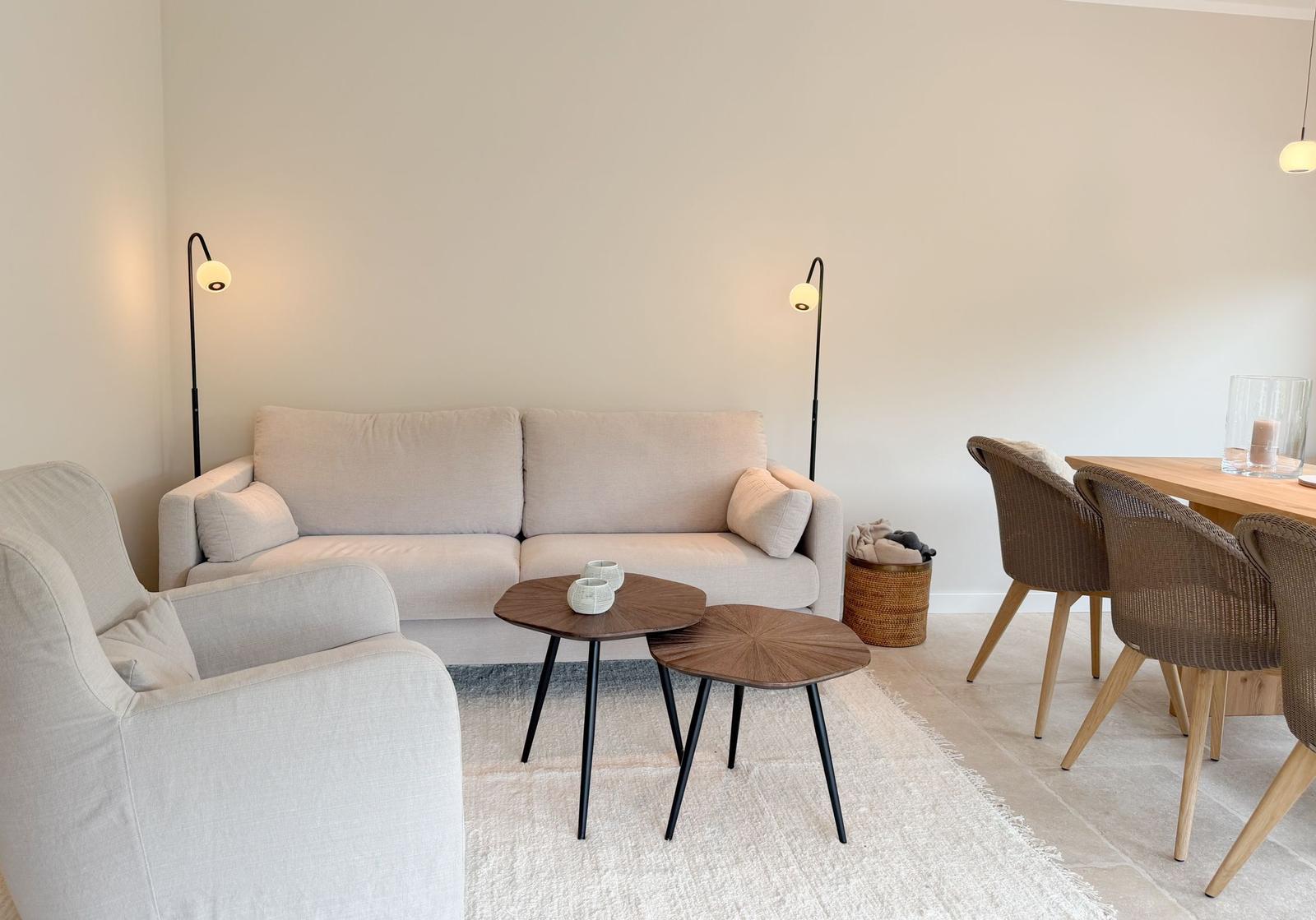 Wohn- und Essbereich mit Sofa, Sessel, zwei Tischen und Stühlen.