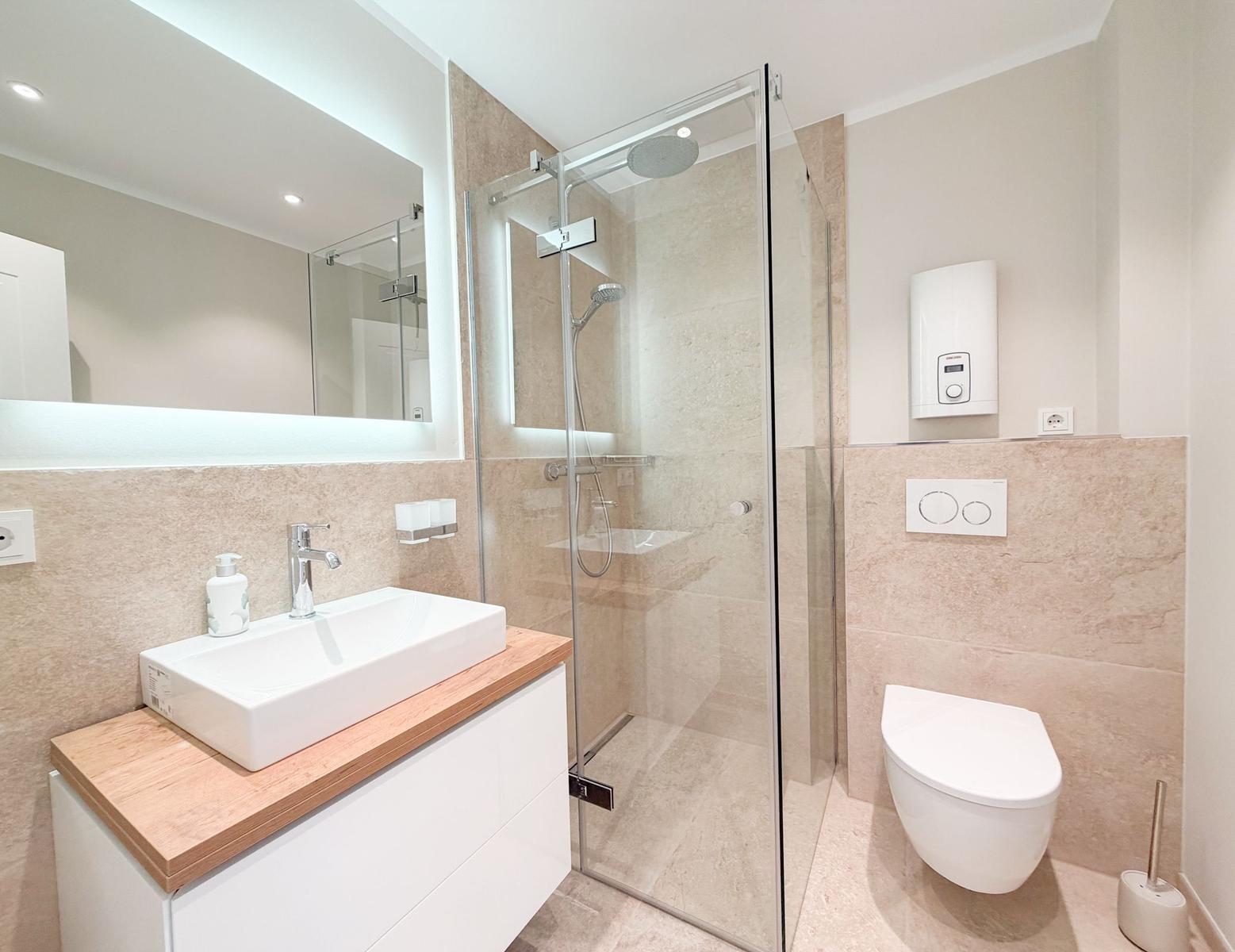 Badezimmer mit Dusche, Waschbecken und Toilette.