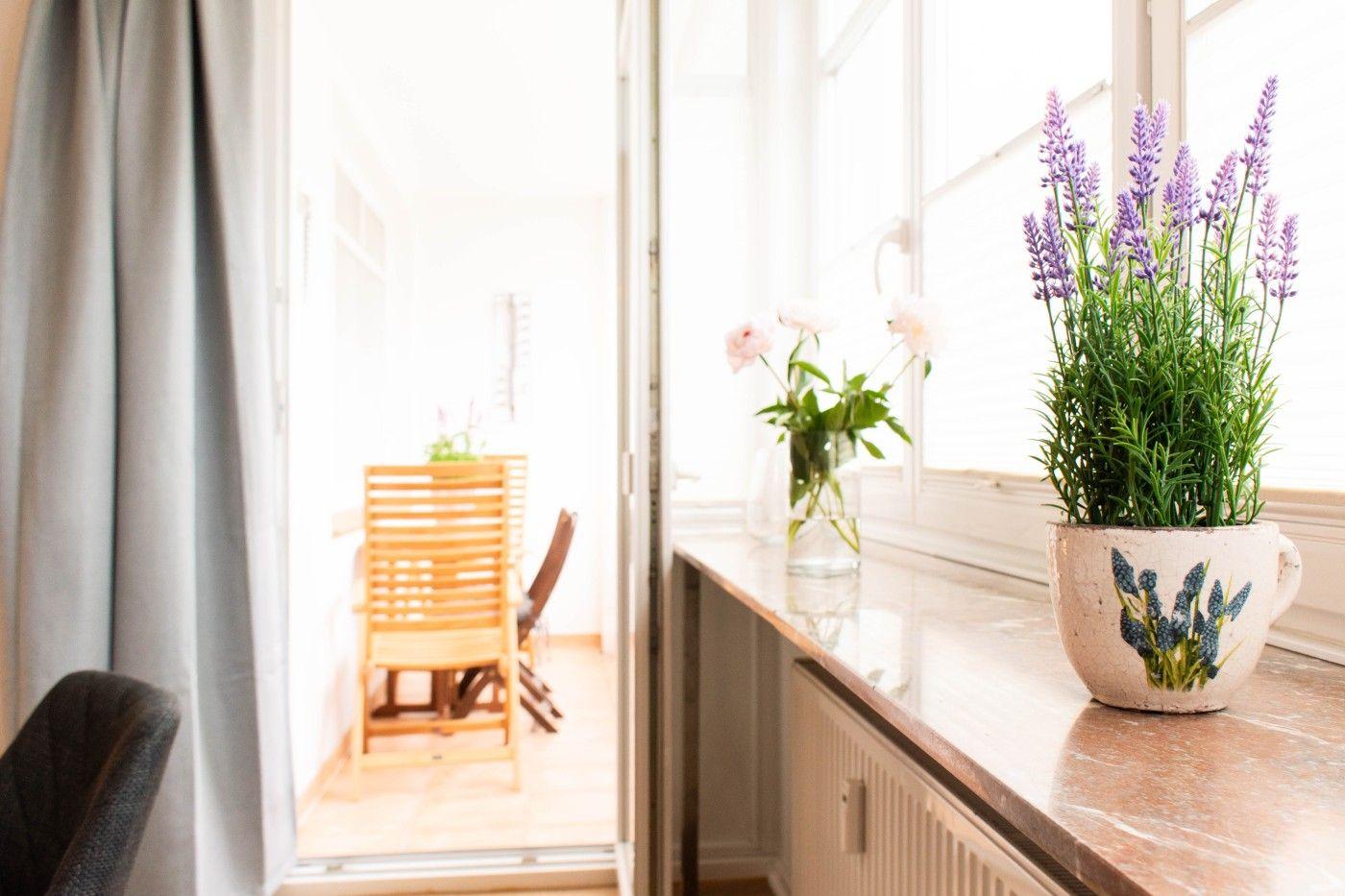 Blick auf Balkon mit Holzstuhl. Fensterbank mit Lavendel und Blumen.