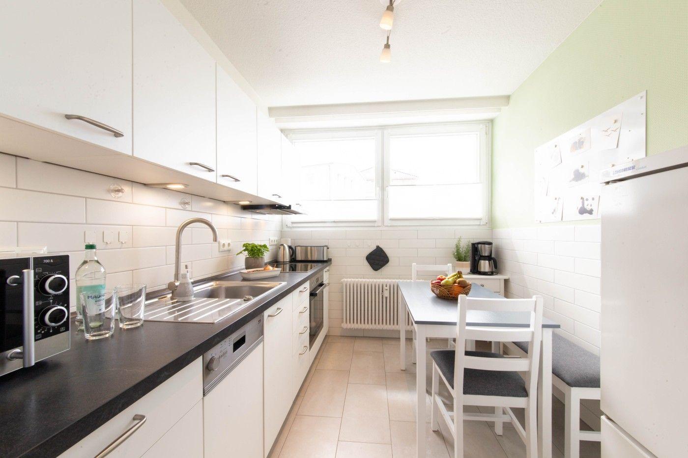 Küche mit Arbeitsplatte, Spüle und Essbereich mit Tisch und Stühlen.
