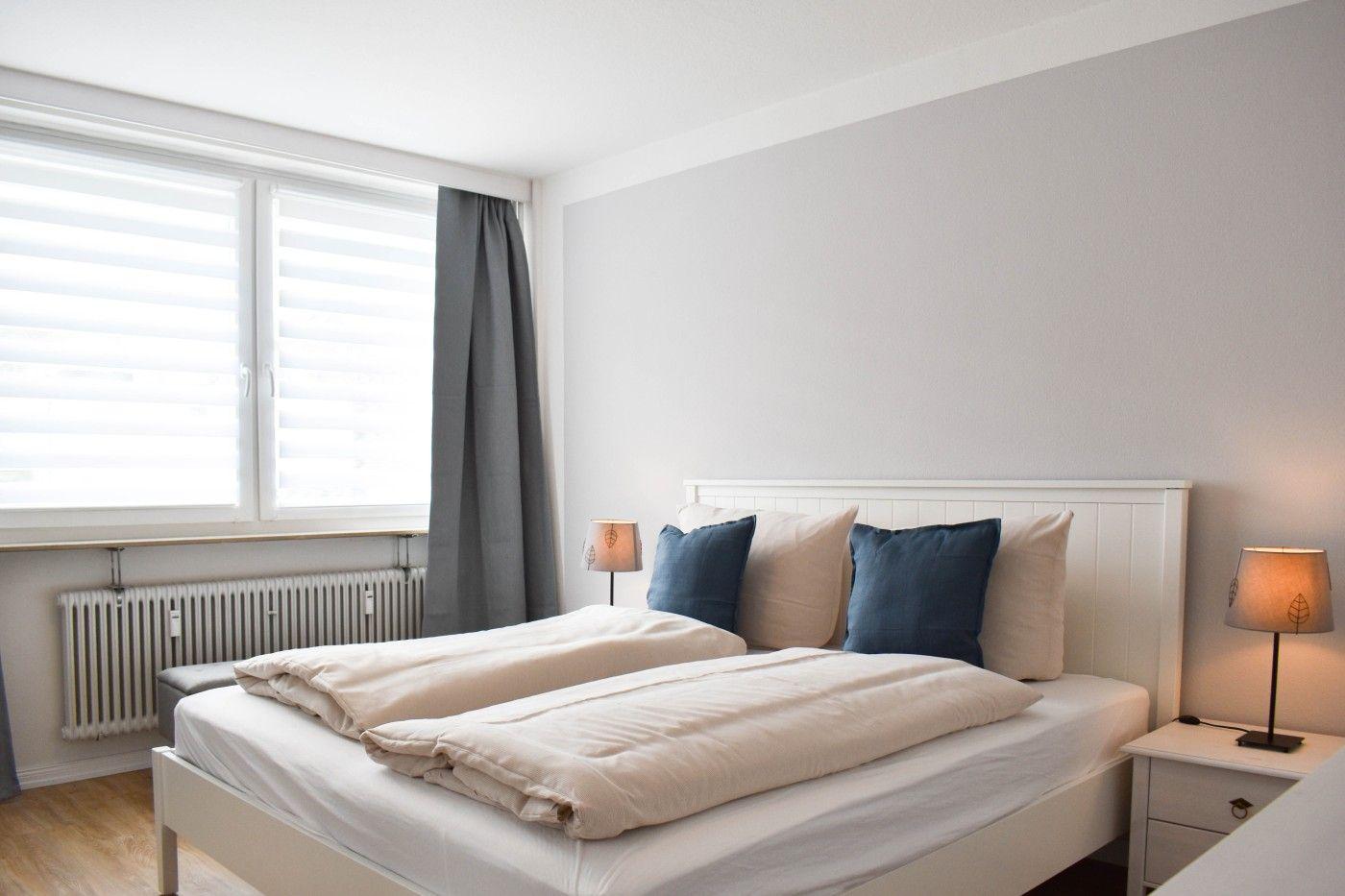 Ein Schlafzimmer mit Doppelbett, zwei Nachttischen und einem Fenster mit Jalousien.