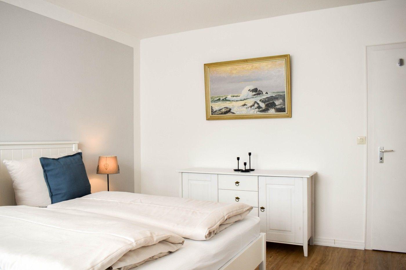Schlafzimmer mit Bett, Nachttisch und Wandbild an der Wand.