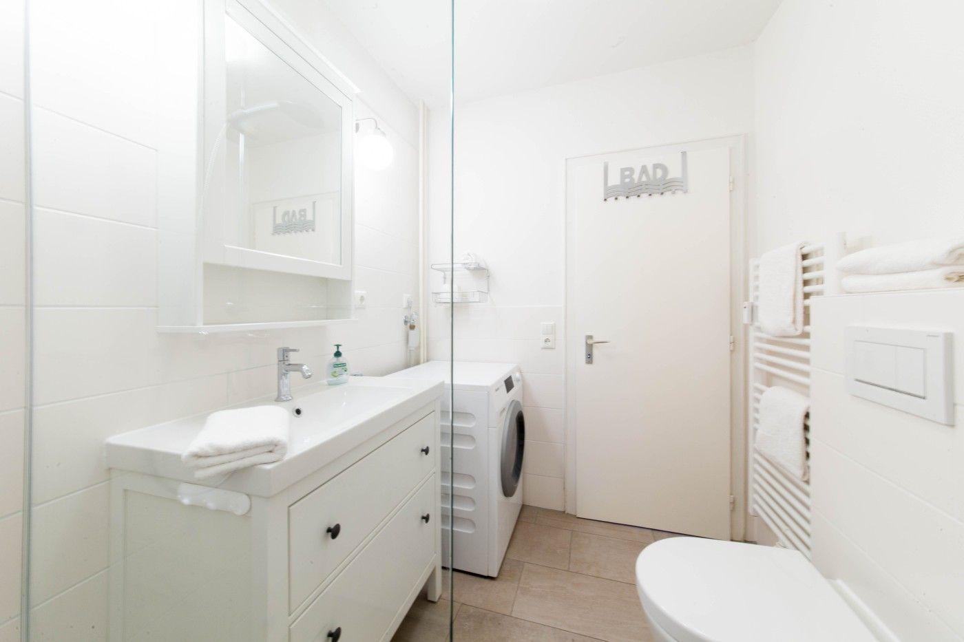 Badezimmer mit Waschmaschine, Spiegelschrank und Heizkörper mit Handtüchern.