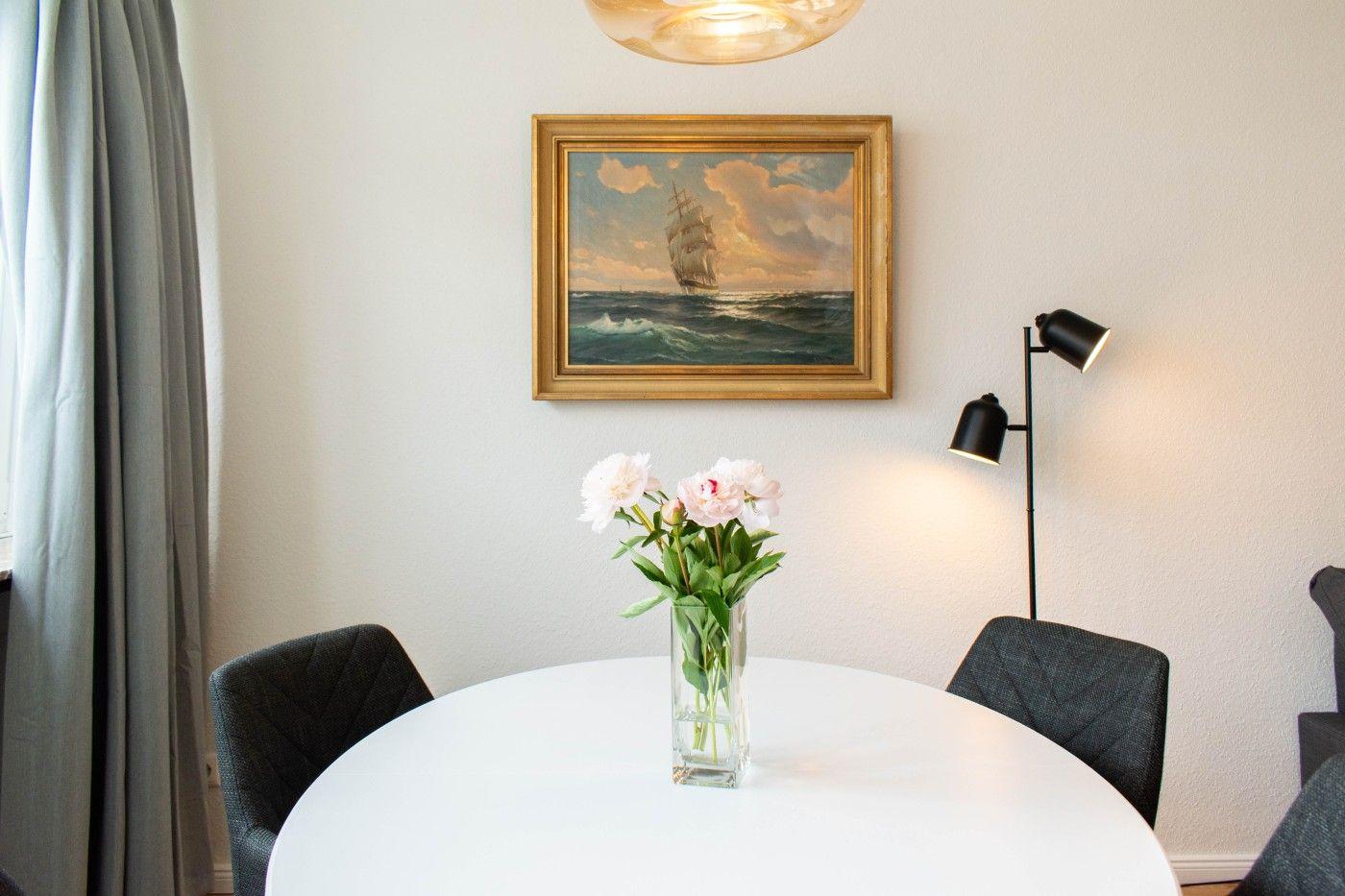 Runder Tisch mit Blumen, Wandbild und Stehlampe