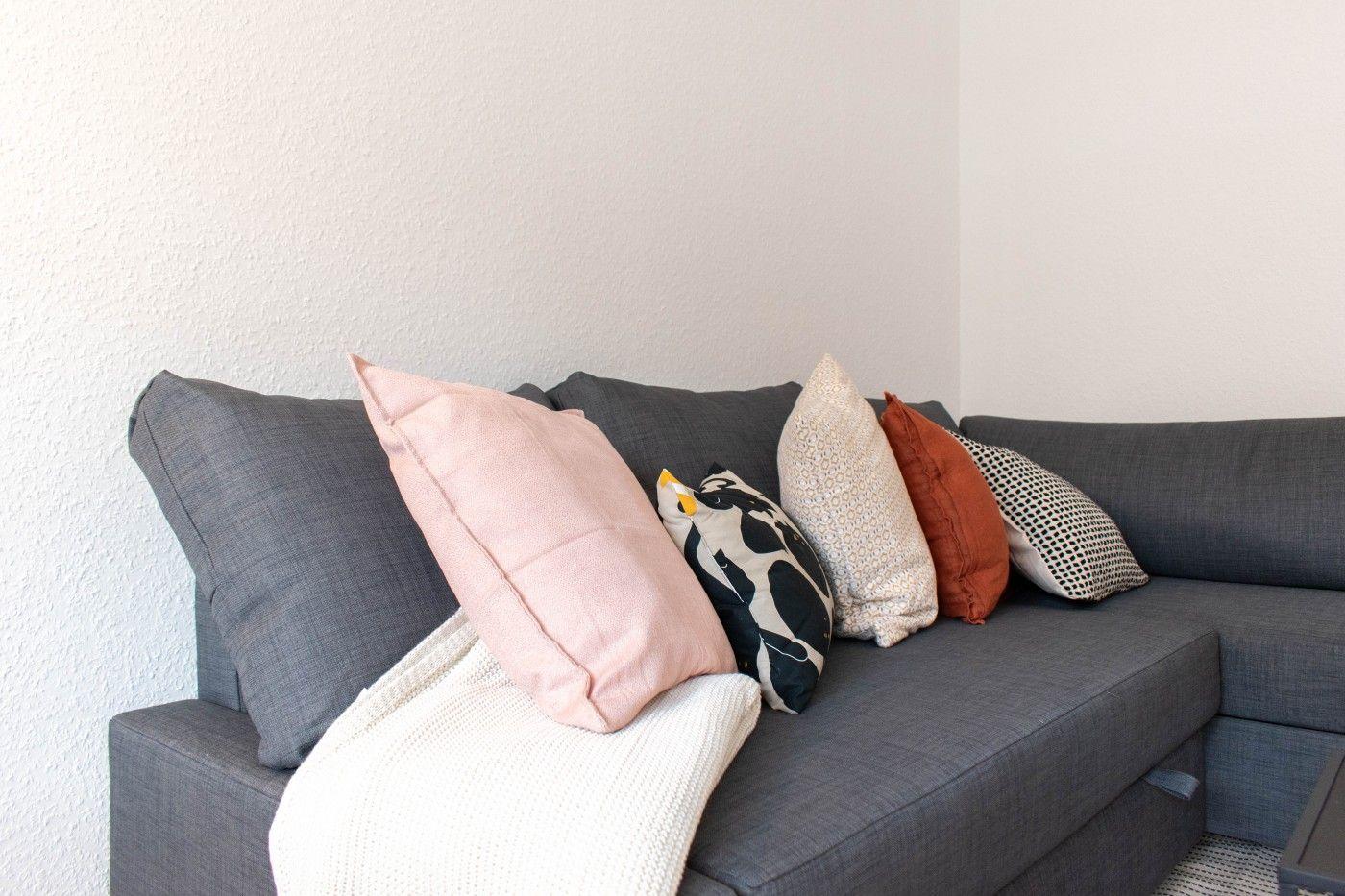 Graße Couch mit mehreren Kissen und einer Decke.