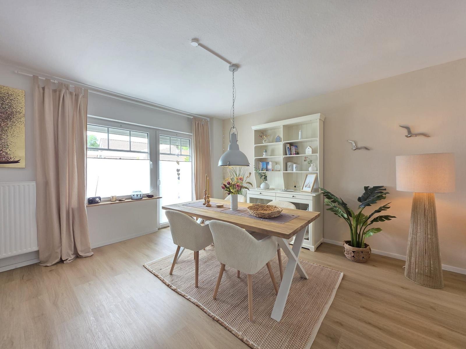 Esszimmer mit Holztisch, Stühlen und Bücherregal an der Wand.