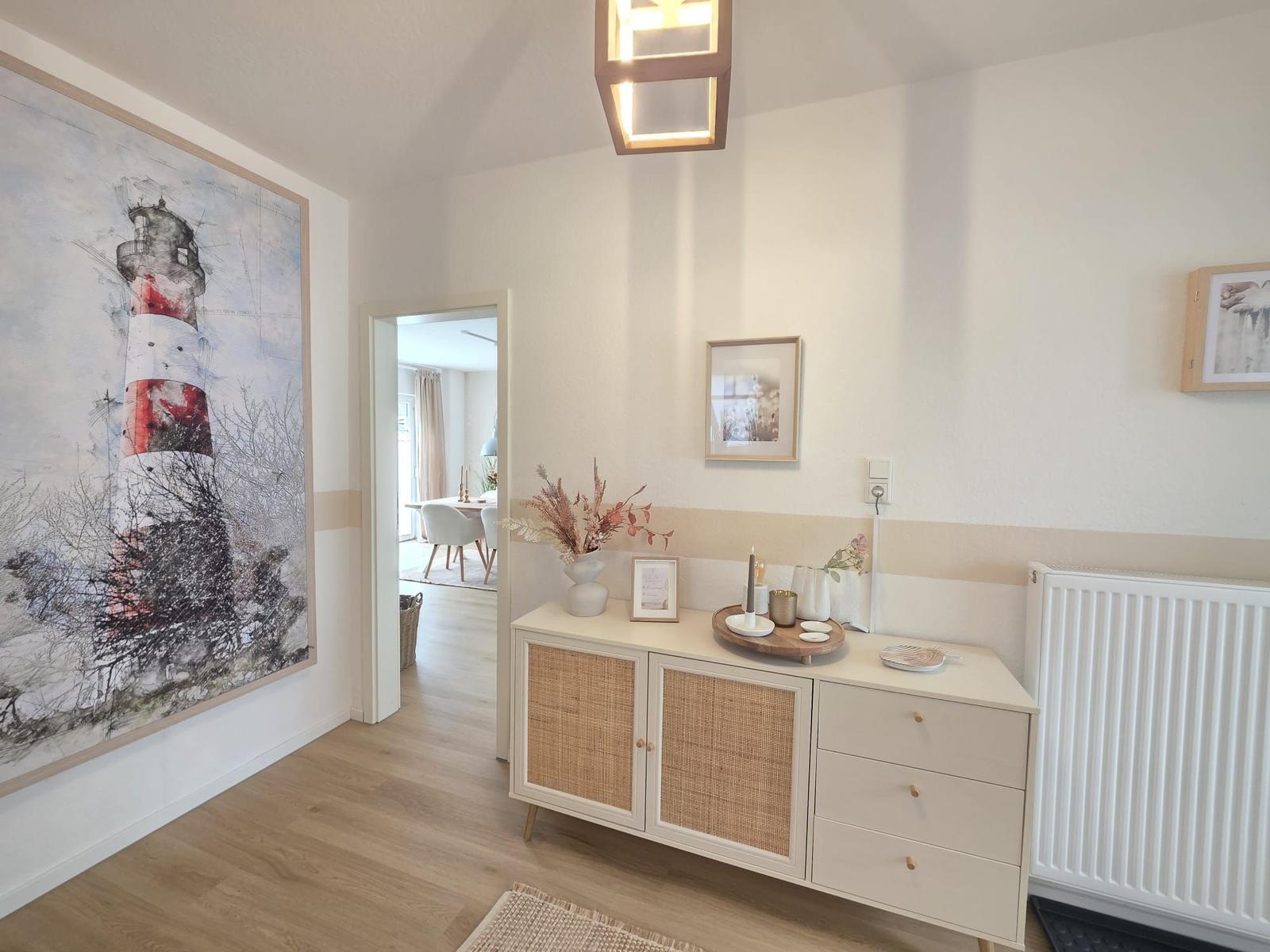 Eingangsbereich mit Sideboard, Wandbild und Licht. Durchgang in die Küche.