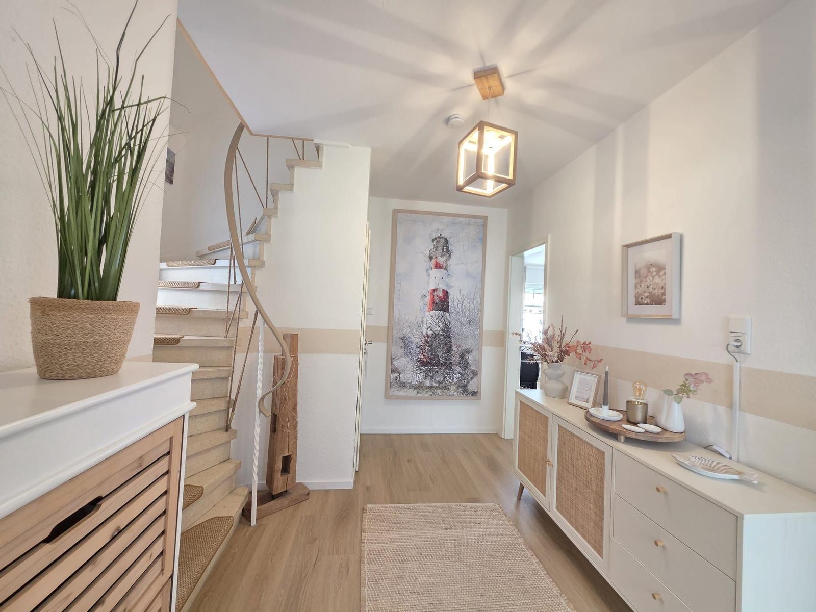 Hausgang mit Treppe, Wandbild Leuchtturm und Schrank mit Korbfronten.