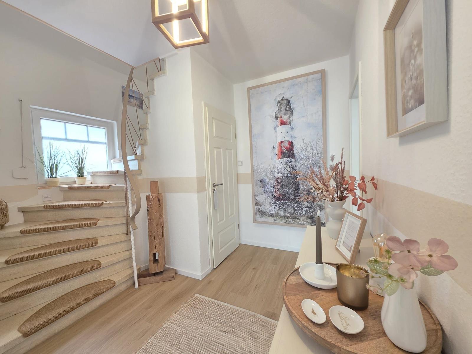 Eingangsbereich mit Treppe, Wandbild und Dekorationsgegenständen.