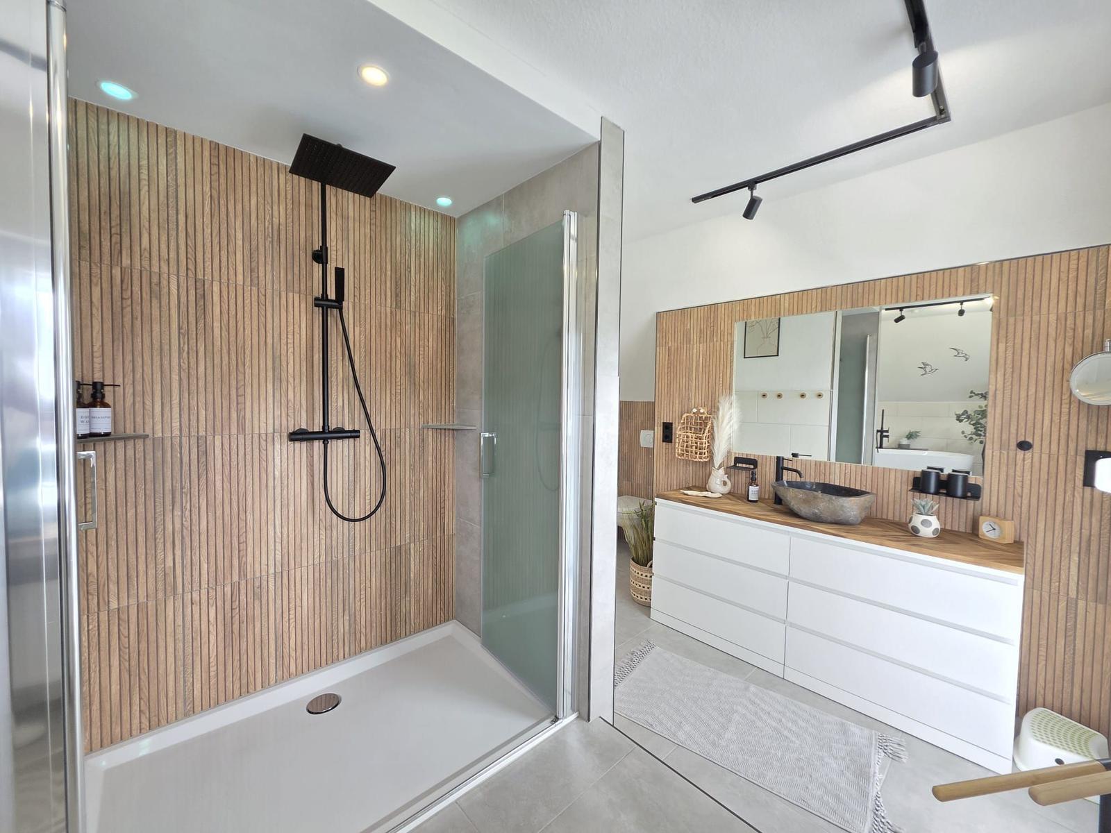 Dusche mit Glaswand und Holzwand, Waschtisch mit Spiegel und Holzplatte