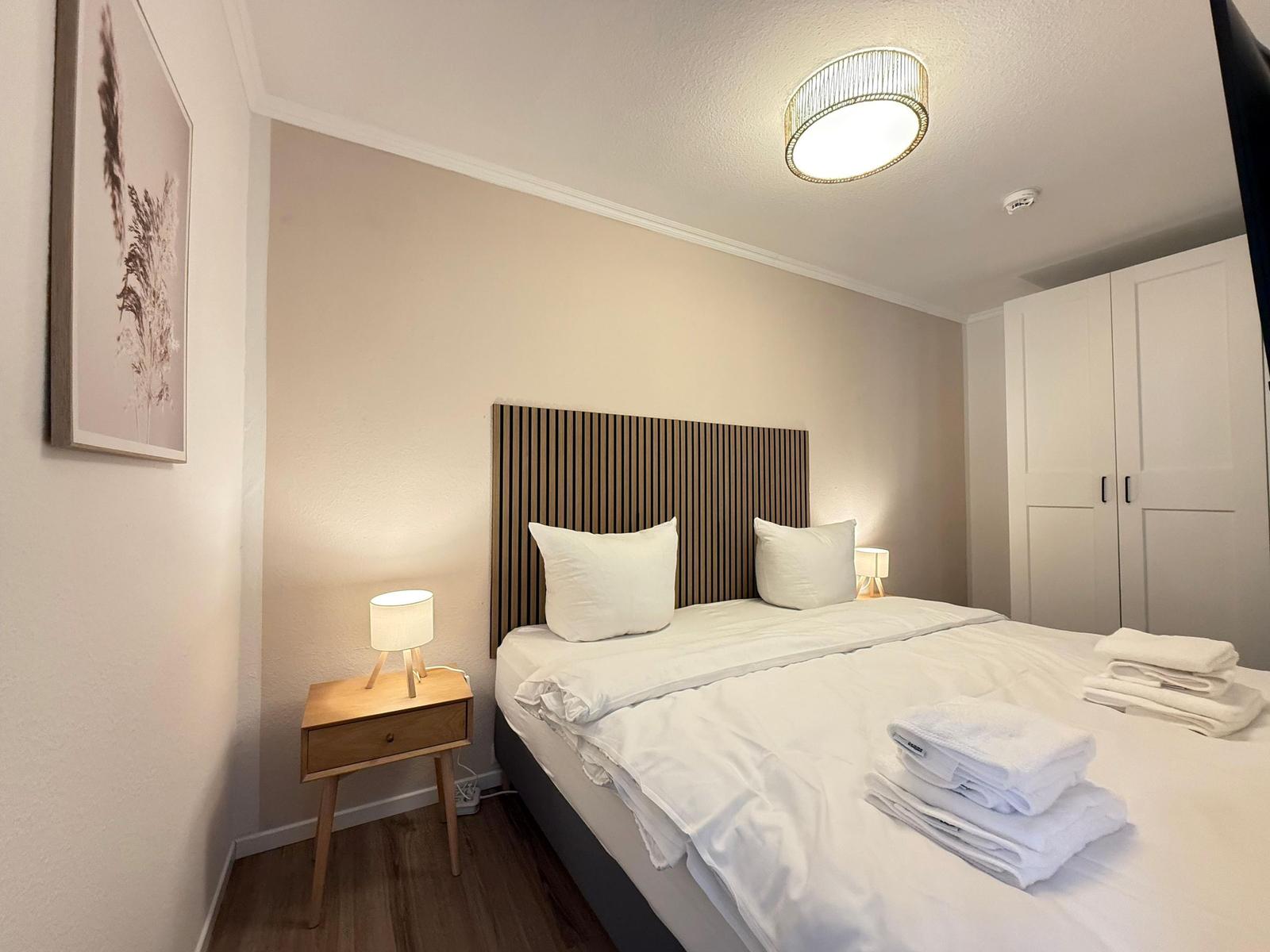 Schlafzimmer mit Bett, Nachttisch und Kleiderschrank.