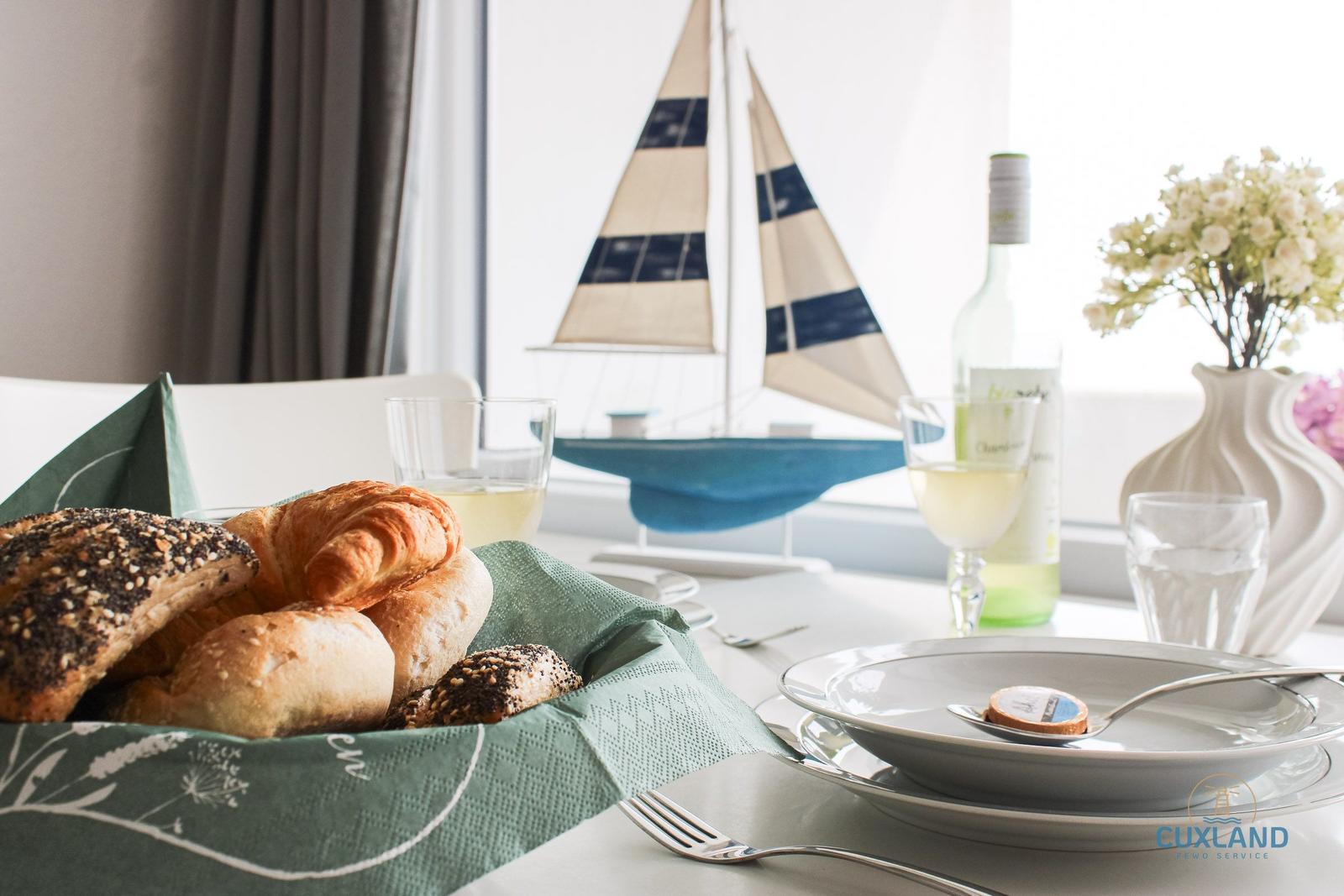 Tisch mit Brot, Wein und Segelbootmodell vor Fenster