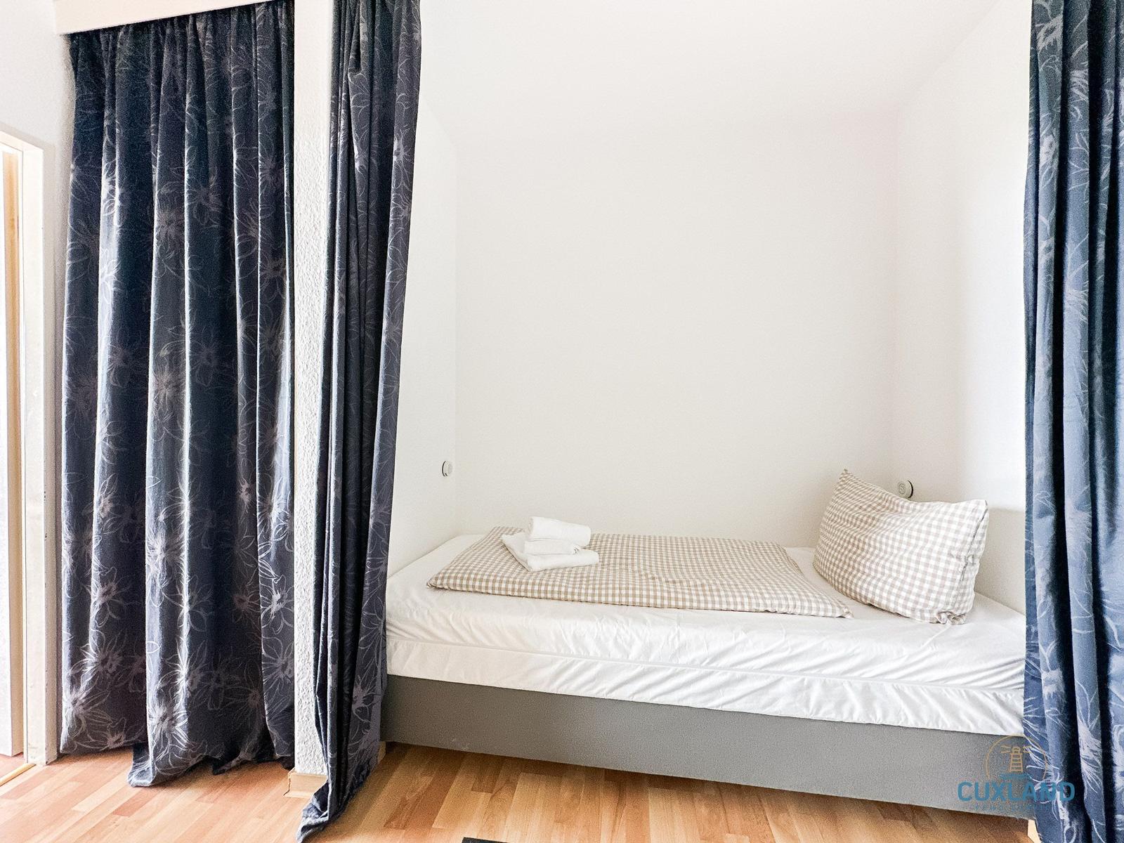 Schlafzimmer mit Bett, Kissen und Vorhängen an den Wänden.