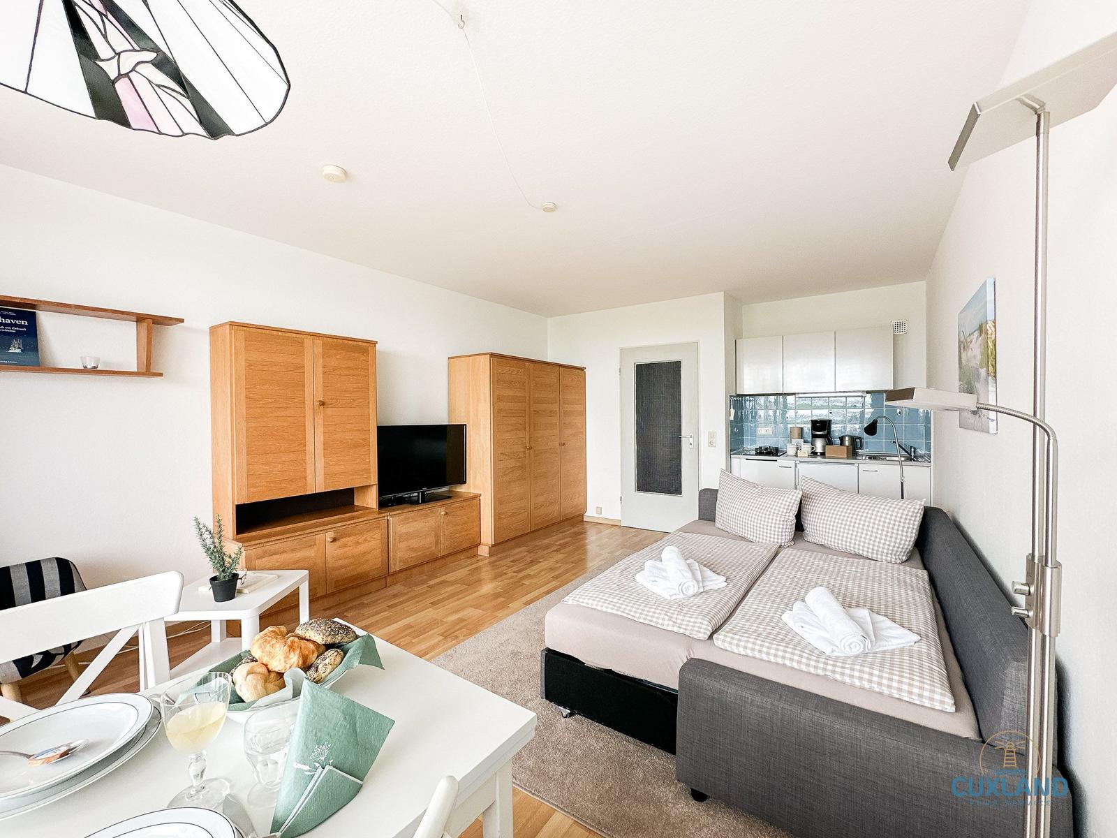 Wohnung mit Essbereich, Schlafsofa und Küche. Holzmöbel und modernes Design.