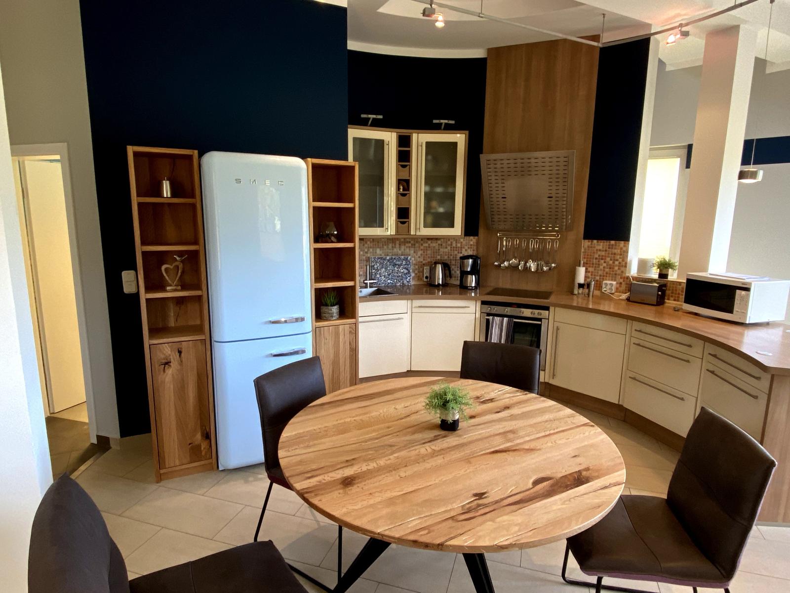Küche mit Essbereich, blauer Kühlschrank und Holztisch mit Stühlen.