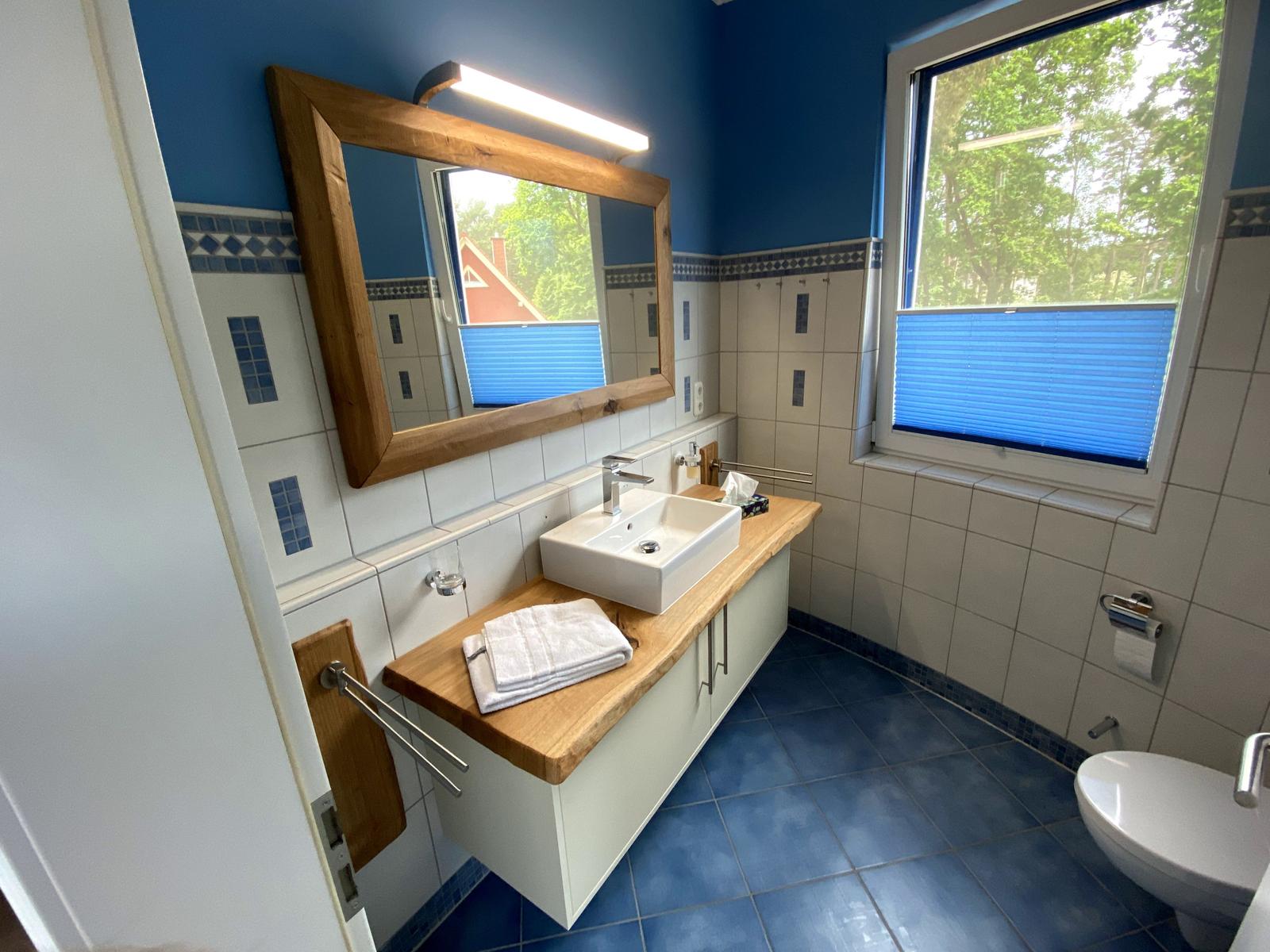 Badezimmer mit blauen Wänden und Boden, Holzwaschtisch und Spiegel.