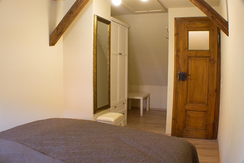 Schlafzimmer mit Bett, Kleiderschrank und Holztür