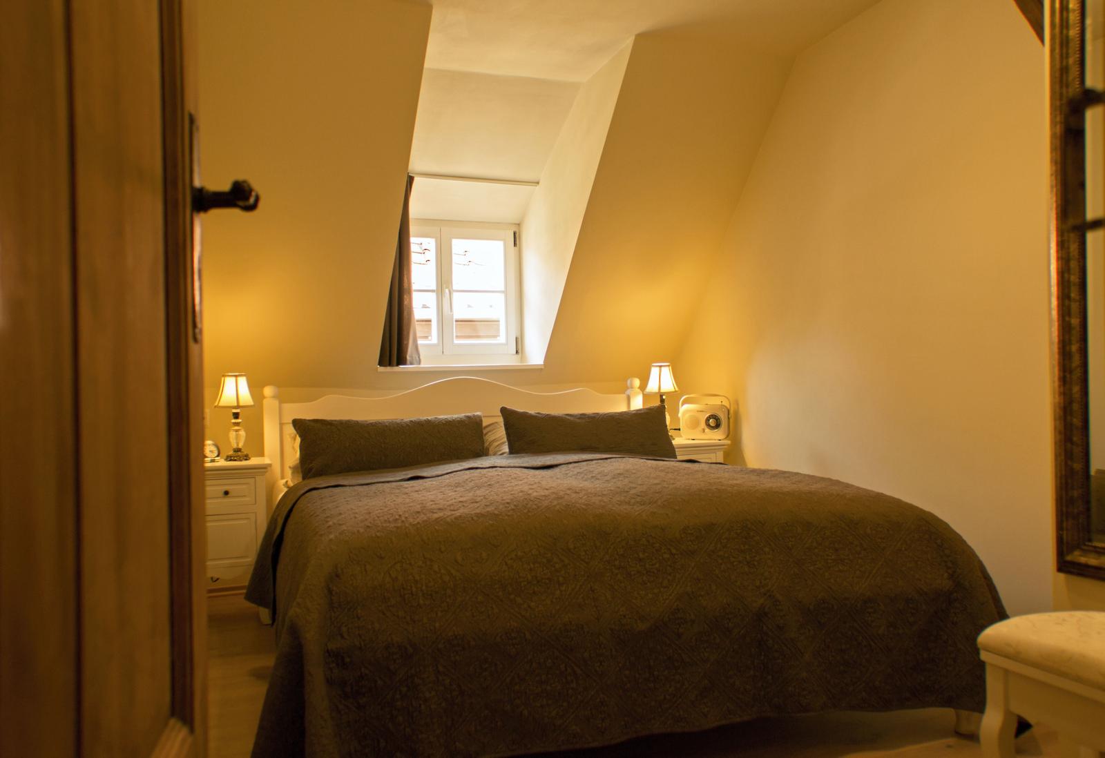 Schlafzimmer mit Dachfenster, Bett, Nachttischen und Lampen.