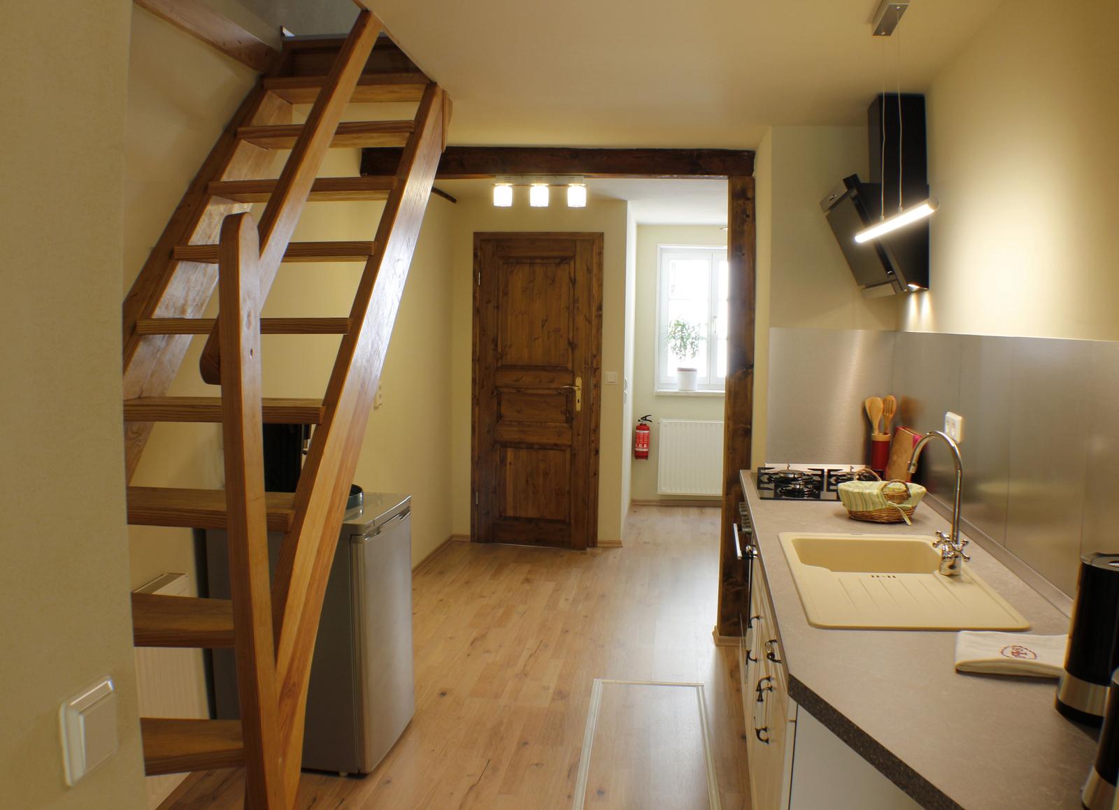 Küche mit Spüle und Holztreppe zur oberen Etage.