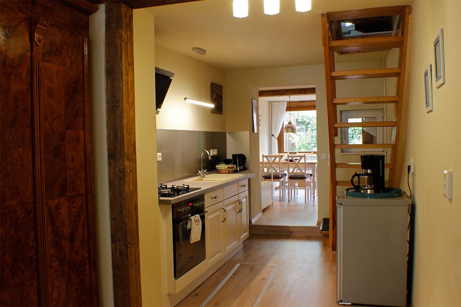 Küche mit Arbeitsfläche, Herd und Kühlschrank. Treppe führt zu einem Dachboden.