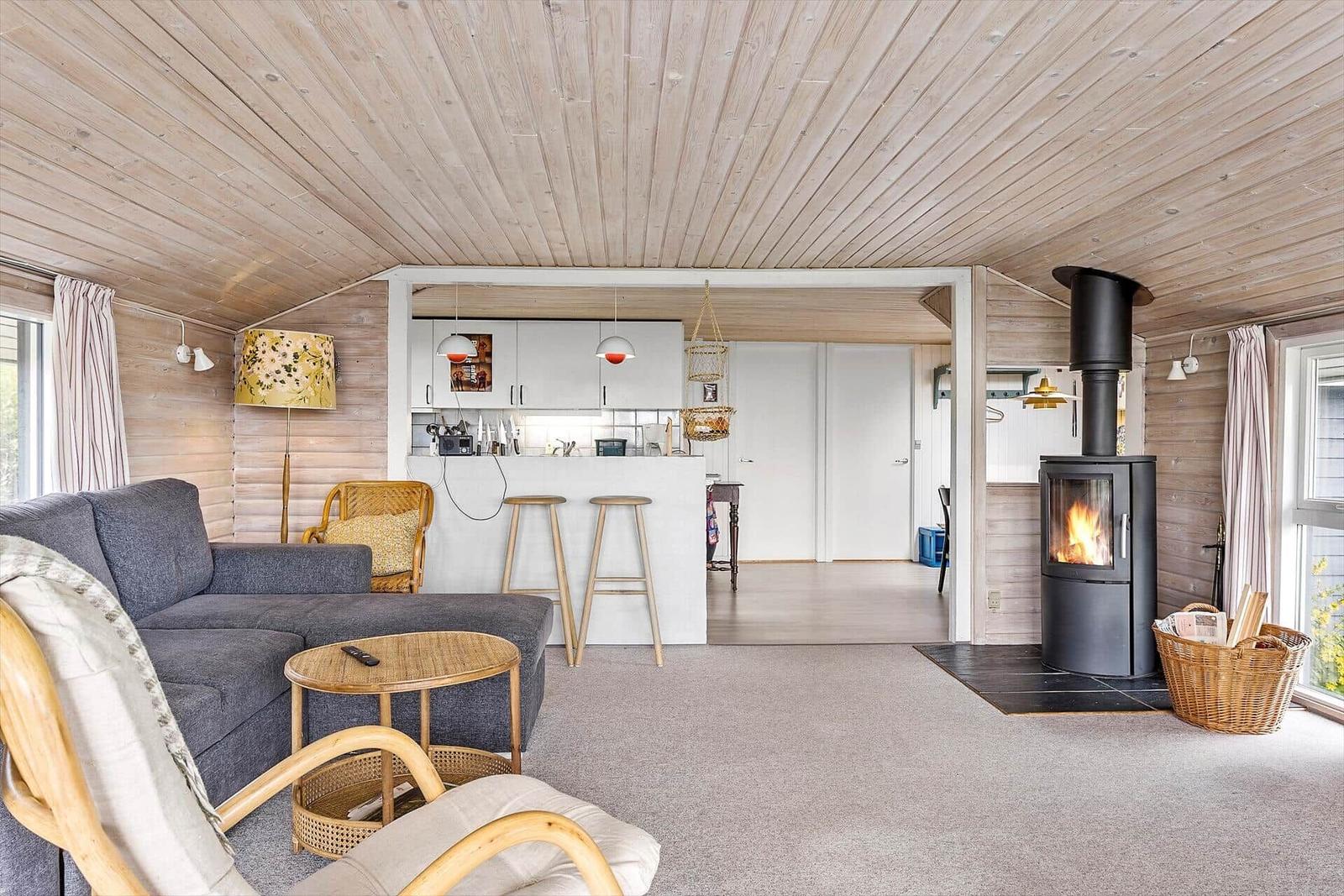 Wohnzimmer mit Kamin, Sofa und Küchenbereich im Hintergrund.