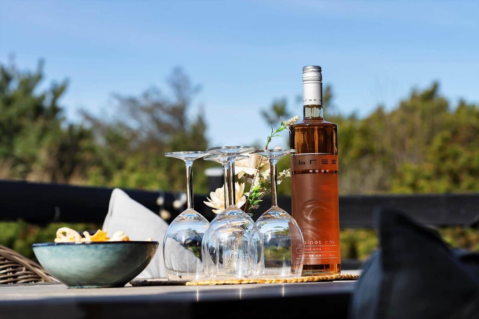 Auf der Terrasse steht eine Flasche Rosé und vier Weingläser mit einer Schale Snacks.