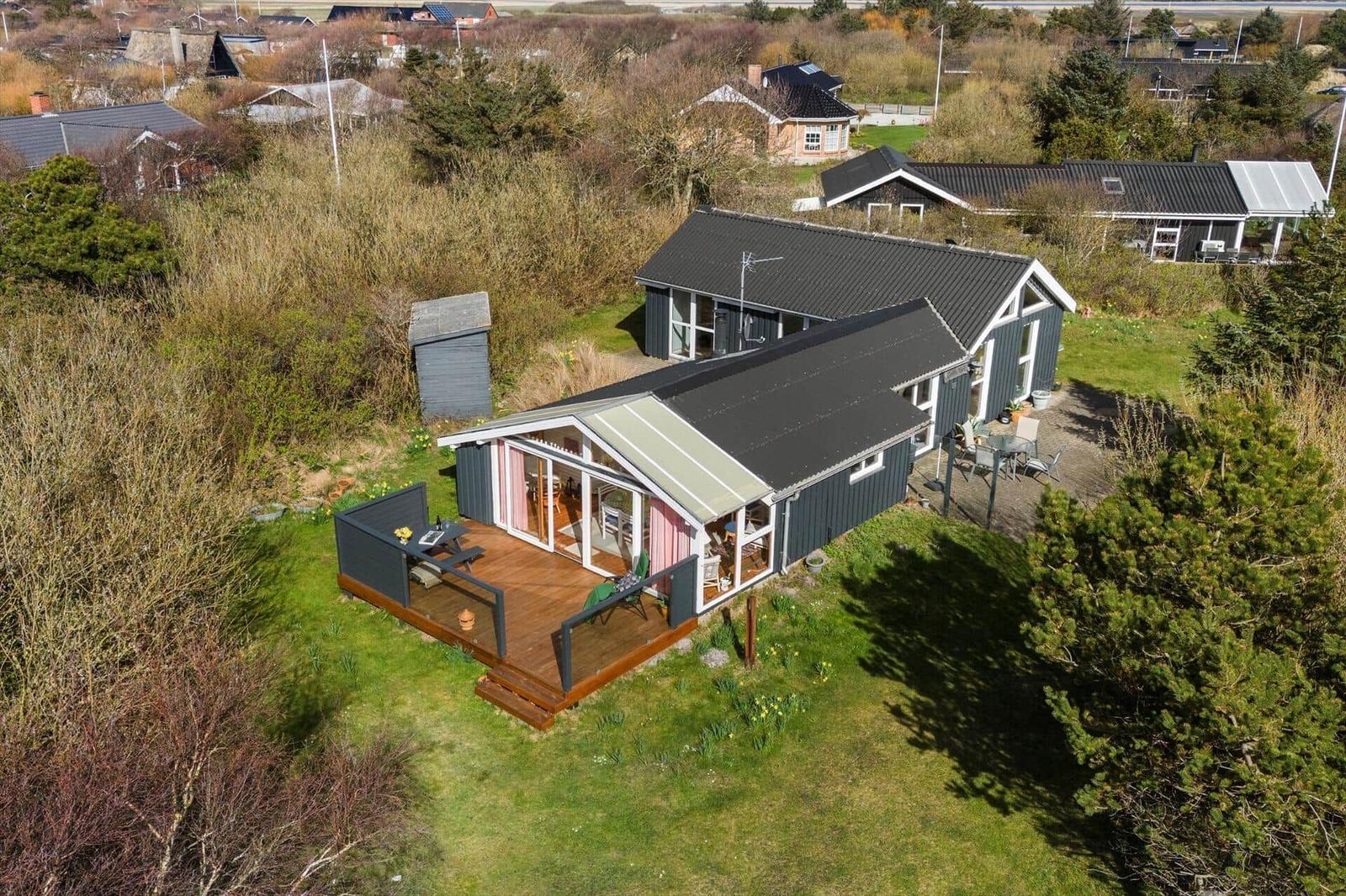Moderne Ferienhaus mit großem Holzterrasse und Garten. Blick auf umliegende Häuser.