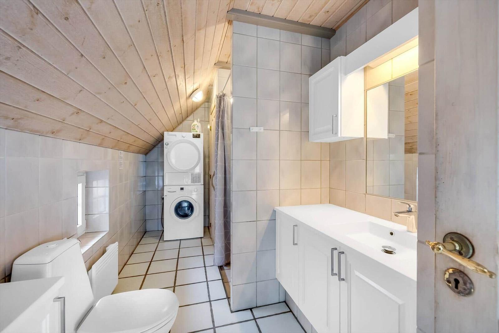 Badezimmer mit Waschmaschine, Toilette und Spiegelschrank.