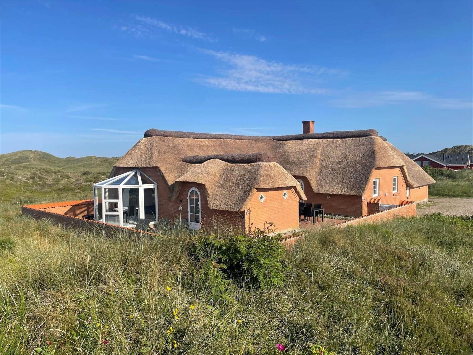 Haus mit Strohdach und Glasveranda in Grasland
