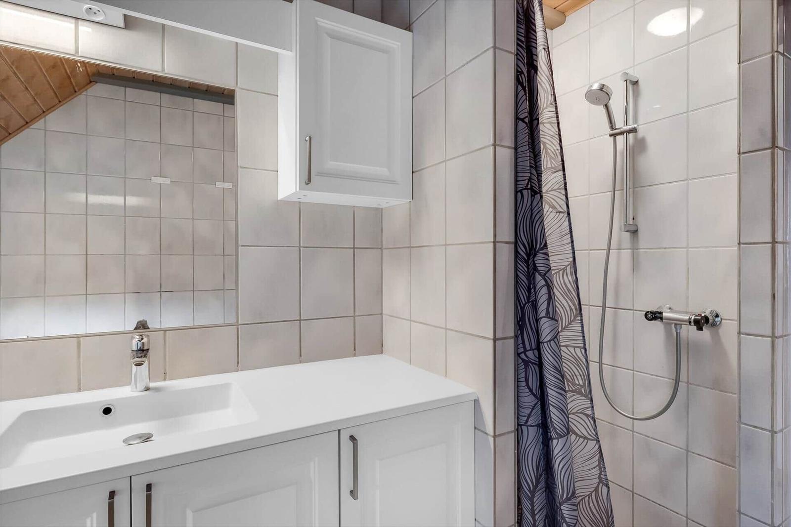Badezimmer mit Dusche, Waschbecken und Spiegel.