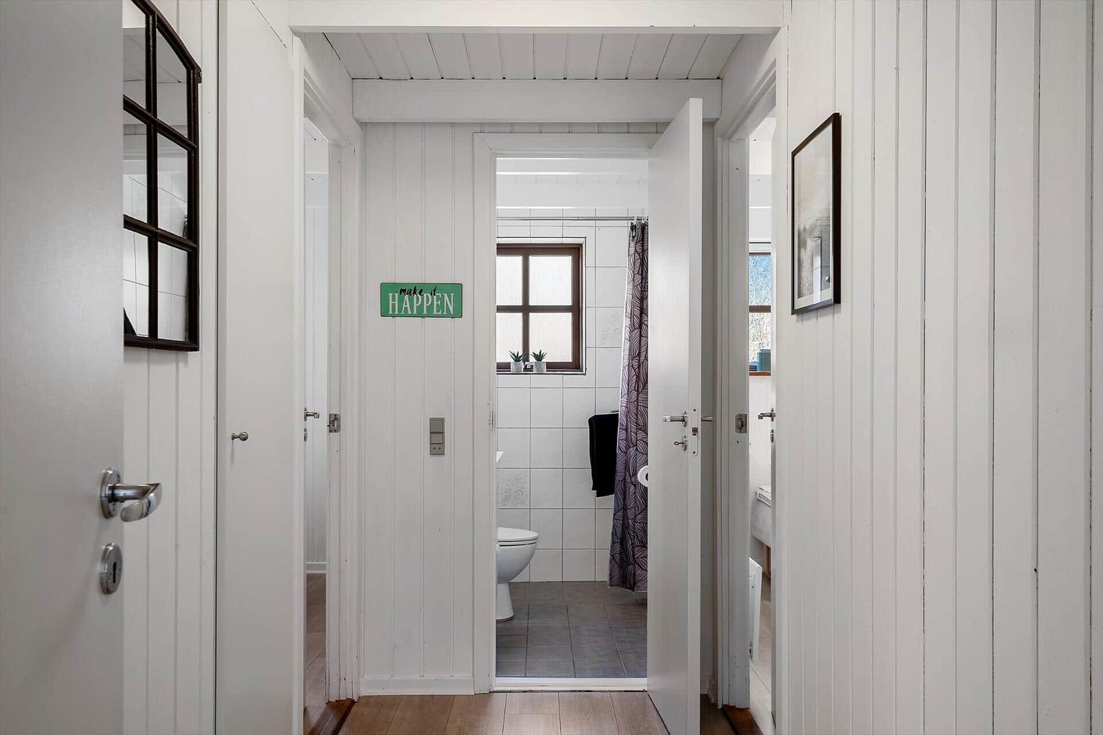 Badezimmer mit Dusche und Toilette, weiße Wände und Holzboden.