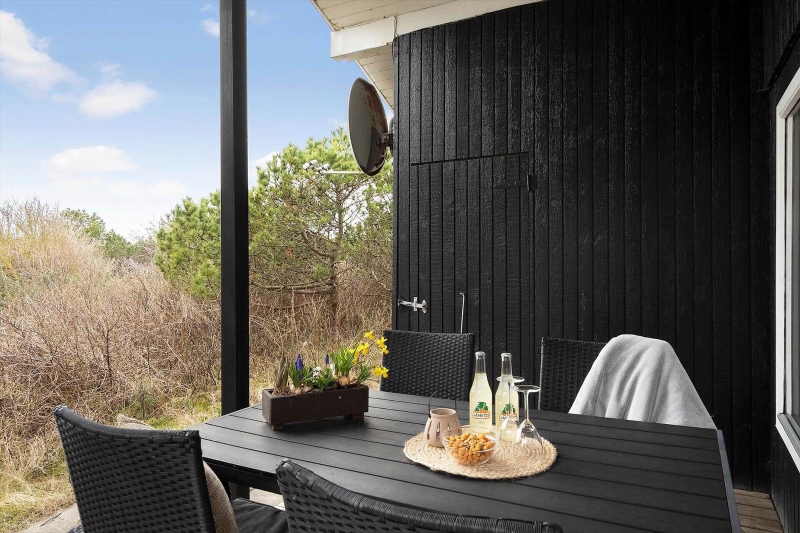 Terrasse mit Tisch und Stühlen, Blick auf Grünflächen und einen Satelliten