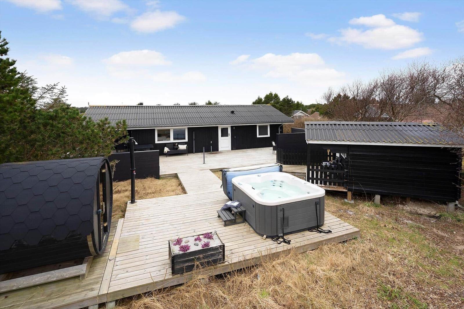 Haus mit Whirlpool, Holzterrasse und Sauna im Freien.